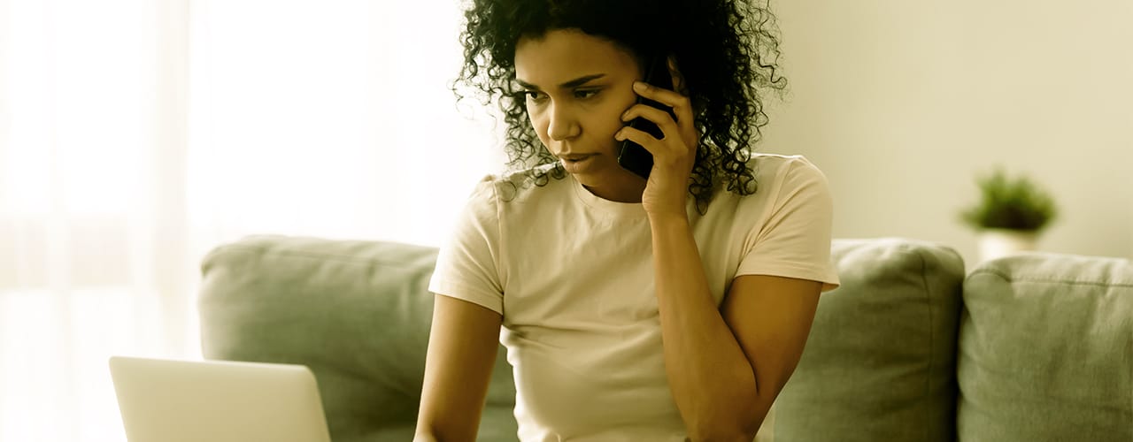 Photo of a female on her mobile while looking at a laptop