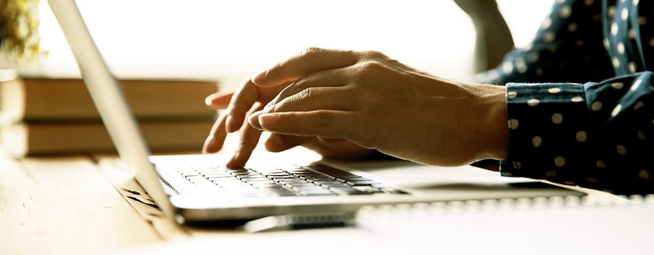 Photo of hands typing on a laptop