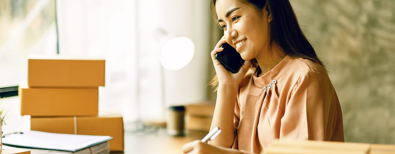 Photo of a woman smiling while talking on her mobile phone